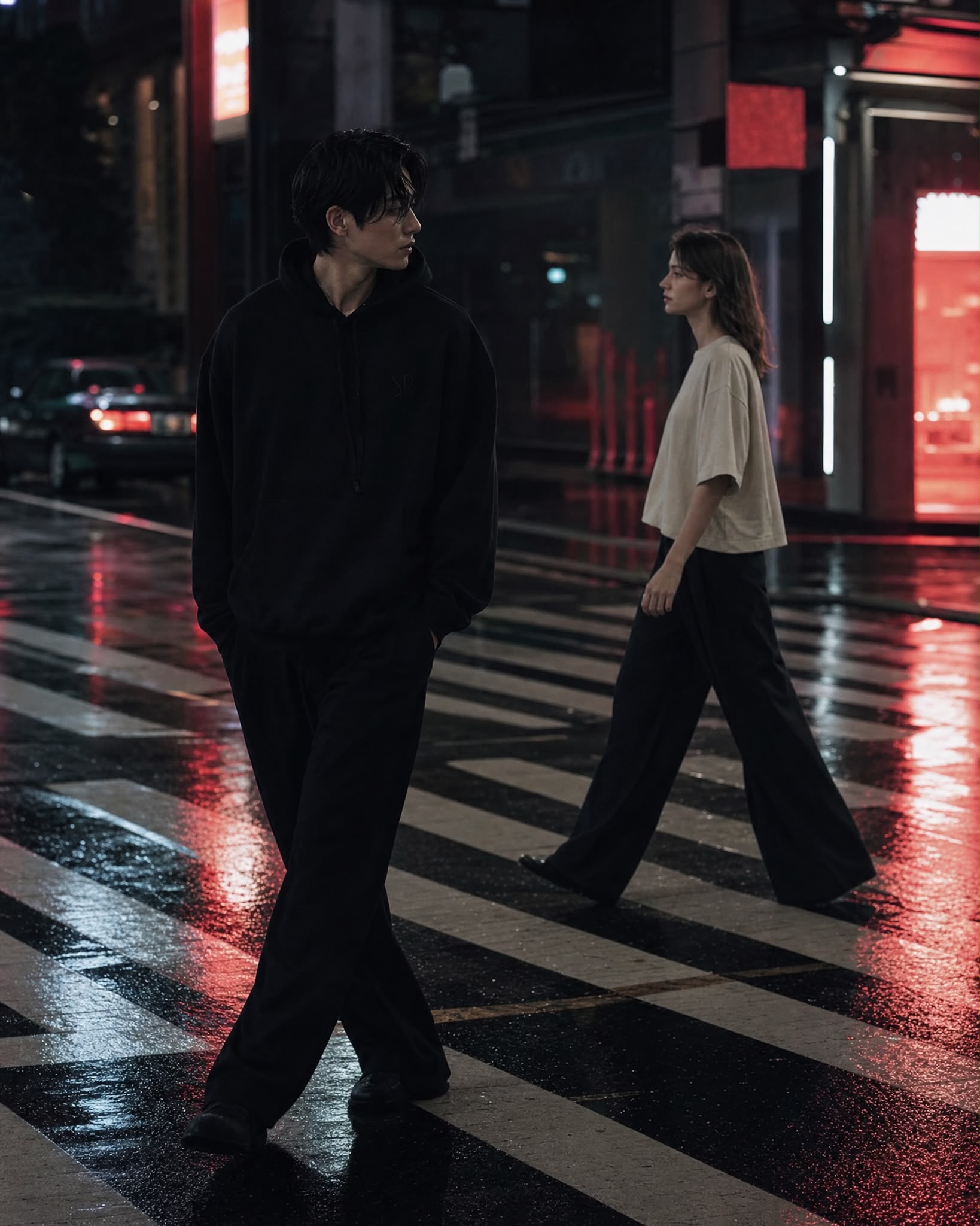 Deux silhouettes traversant une rue de Séoul sous la pluie, la nuit